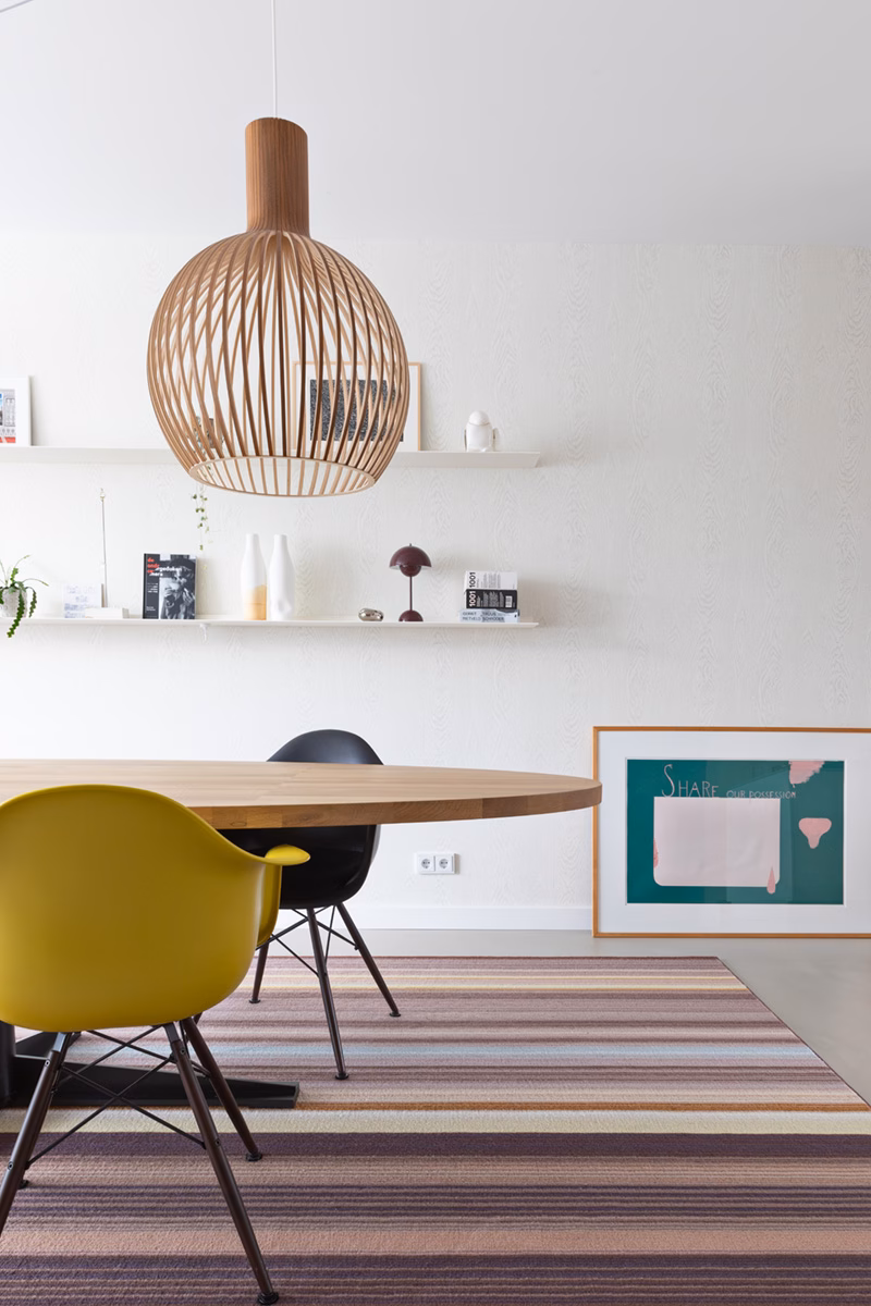 kleurrijk kleed met gele eames stoel